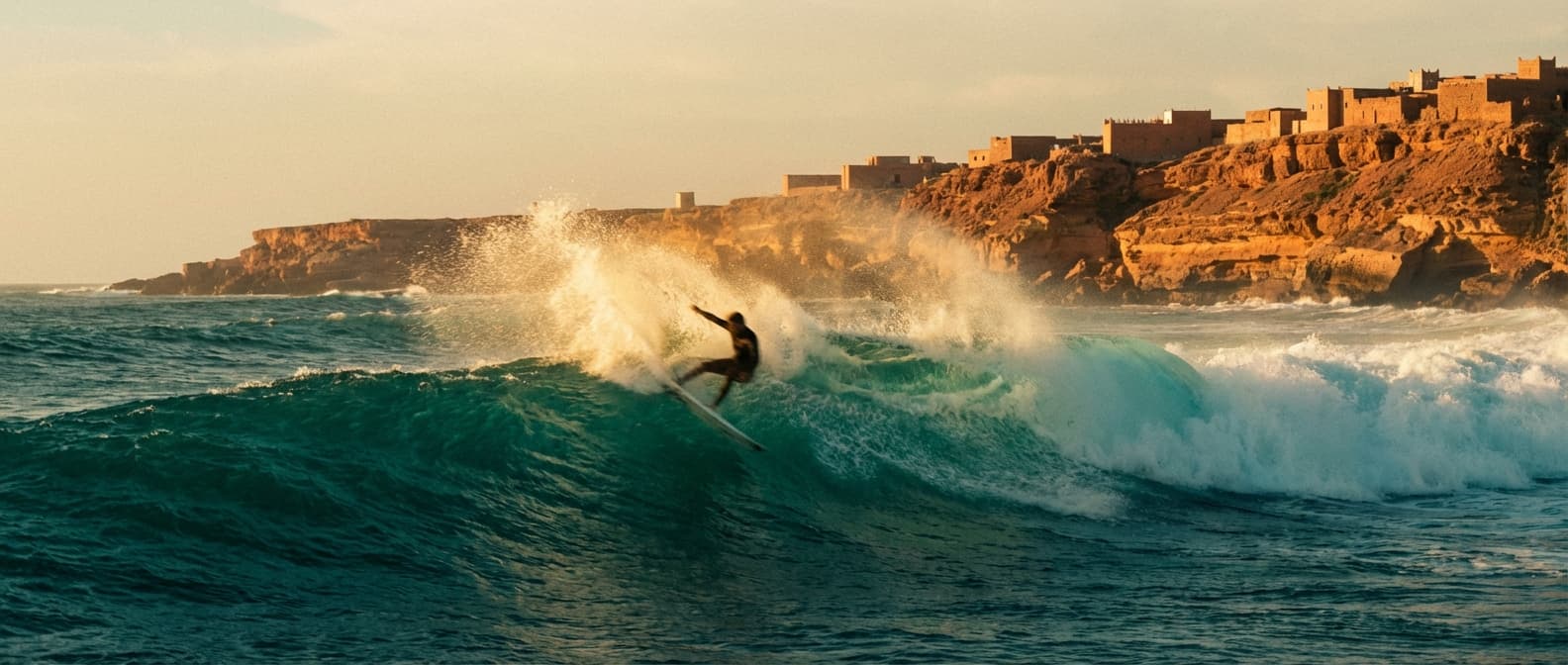 Surfer carving a wave at sunset with a Moroccan kasbah in the background